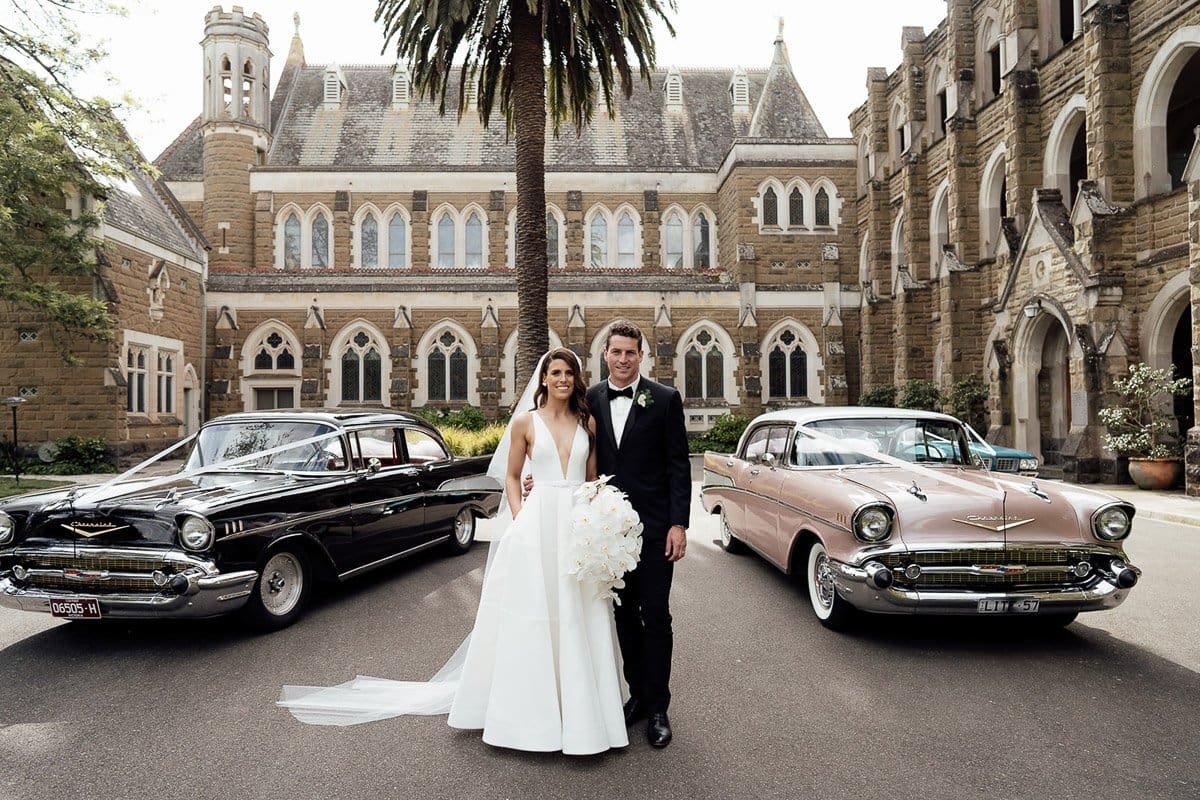 Bride And Groom Standing In Front Of Their Wedding Cars